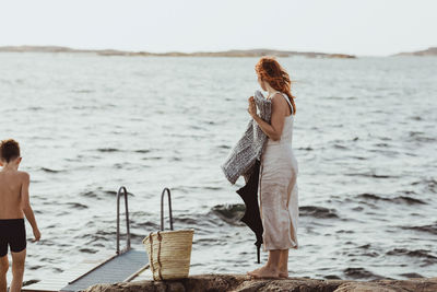 Side view of woman with son standing against sea over archipelago