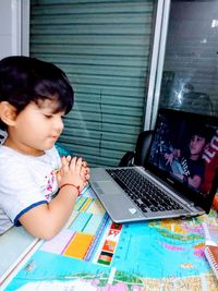 Girl looking away while sitting on table at home