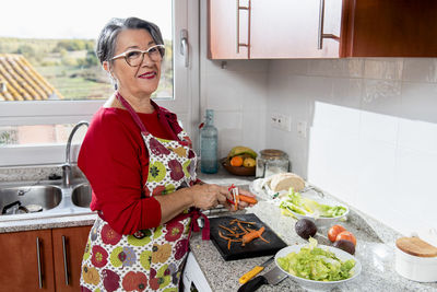 Old lady peeling carrots in the kitchen.