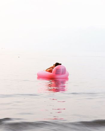 REAR VIEW OF COUPLE KISSING AGAINST SEA