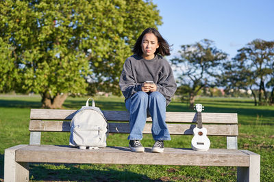 Portrait of young woman standing against trees