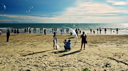 Children playing on beach against sky