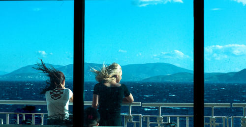 Rear view of woman standing by railing against window