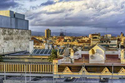 Buildings in city against cloudy sky