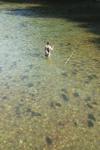 From above male fisherman throwing fishing rod into a mountain river