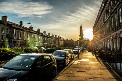 Street amidst buildings in city against dramatic sunset