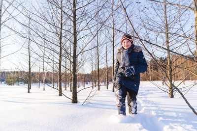 Full length of young woman standing on snow covered field