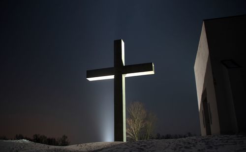 Illuminated cross against clear sky at night