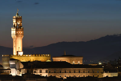 Illuminated buildings in city against sky at night