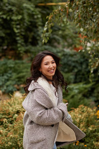 Portrait of young woman standing against plants