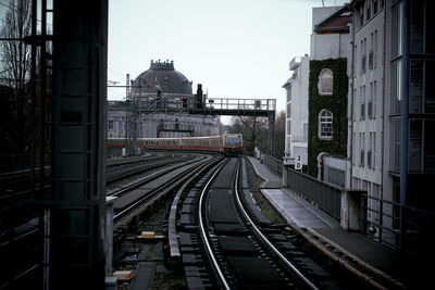 Railroad tracks amidst buildings in city against sky