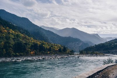 Scenic view of river by mountains against sky