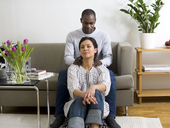 Couple on sofa, man giving woman massage