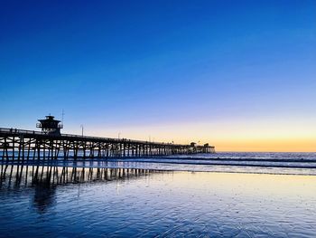 Pier over sea against blue sky