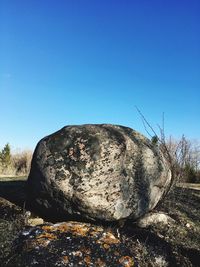 Rock on field against clear blue sky