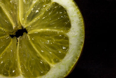 Close-up of lemon slice over water against black background