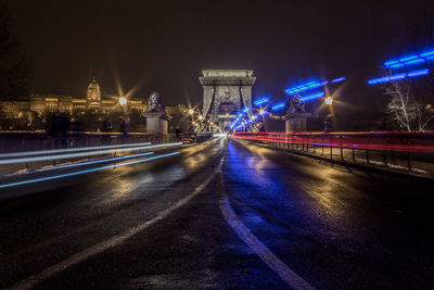 Light rails on road by buda castle against clear sky at night