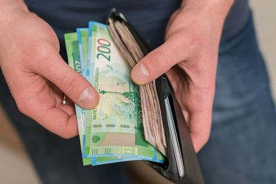 Midsection of man removing paper currency from wallet