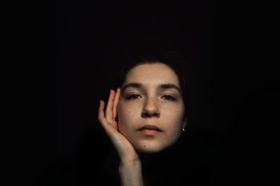 Close-up portrait of a woman over black background