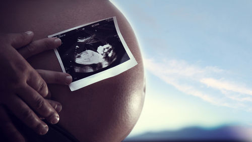 Midsection of woman holding hands against sky