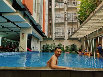 Full length of shirtless man sitting at swimming pool