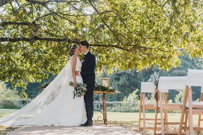 Newlywed couple kissing while standing outdoors