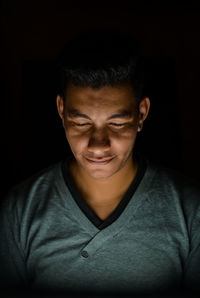 Close-up portrait of a serious young man over black background