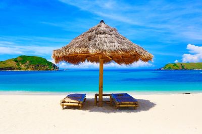 Parasol with seats on beach against sky