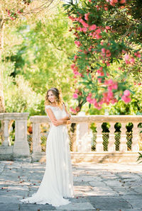 Portrait of young woman standing against trees