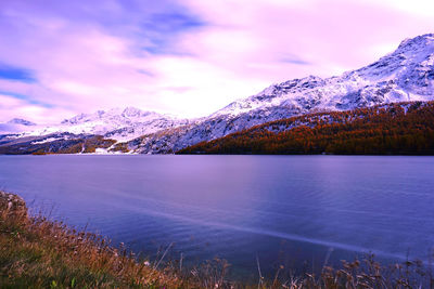 Scenic view of lake by snowcapped mountains against sky