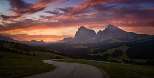 Road leading towards mountains against sky during sunset