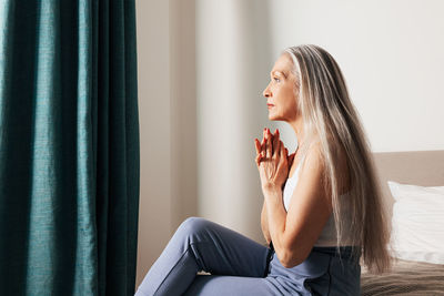 Side view of young woman looking away while sitting at home