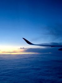 Airplane flying over sea against sky during sunset