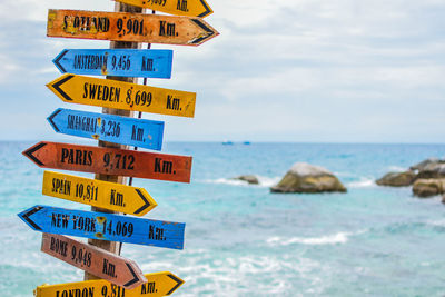 Information sign by sea against sky