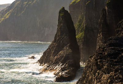 Rock formation by sea against mountain