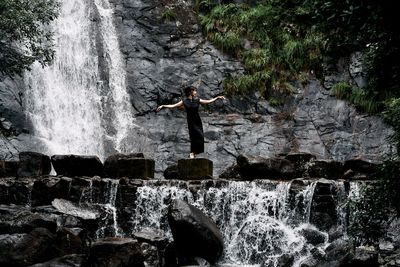 Rear view of man standing against waterfall