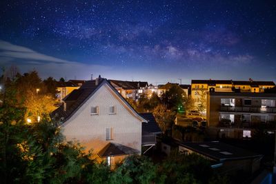 Illuminated houses against sky at night