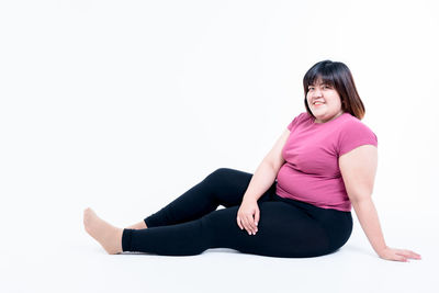 Portrait of woman sitting against white background