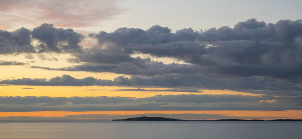 Scenic view of sea against dramatic sky during sunset