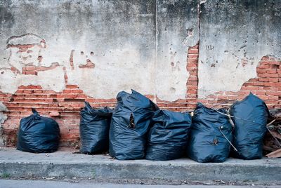 Garbage in plastics on sidewalk against wall