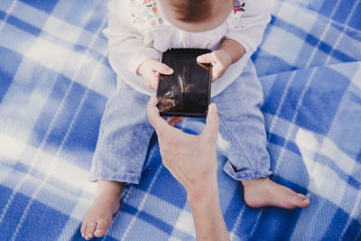 Cropped hand of woman giving phone to baby girl