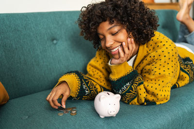 Portrait of woman holding piggy bank on table