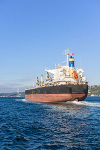 Ship sailing in sea against clear blue sky