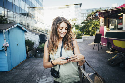 Happy female tourist using smart phone in city