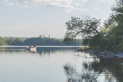 View of man sitting in lake against sky