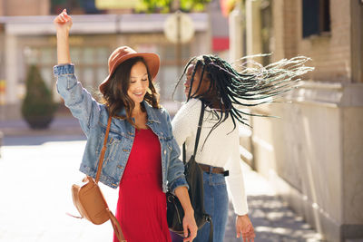 Smiling women dancing outdoors in city