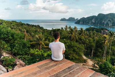 Rear view of man looking at sea against sky