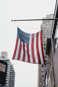 Low angle view of american flag hanging against clear sky in city