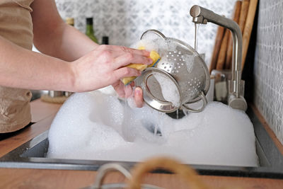 Close-up of a man washing dishes in the kitchen sink