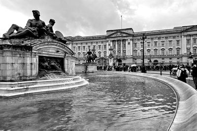 Statue of fountain in city against sky